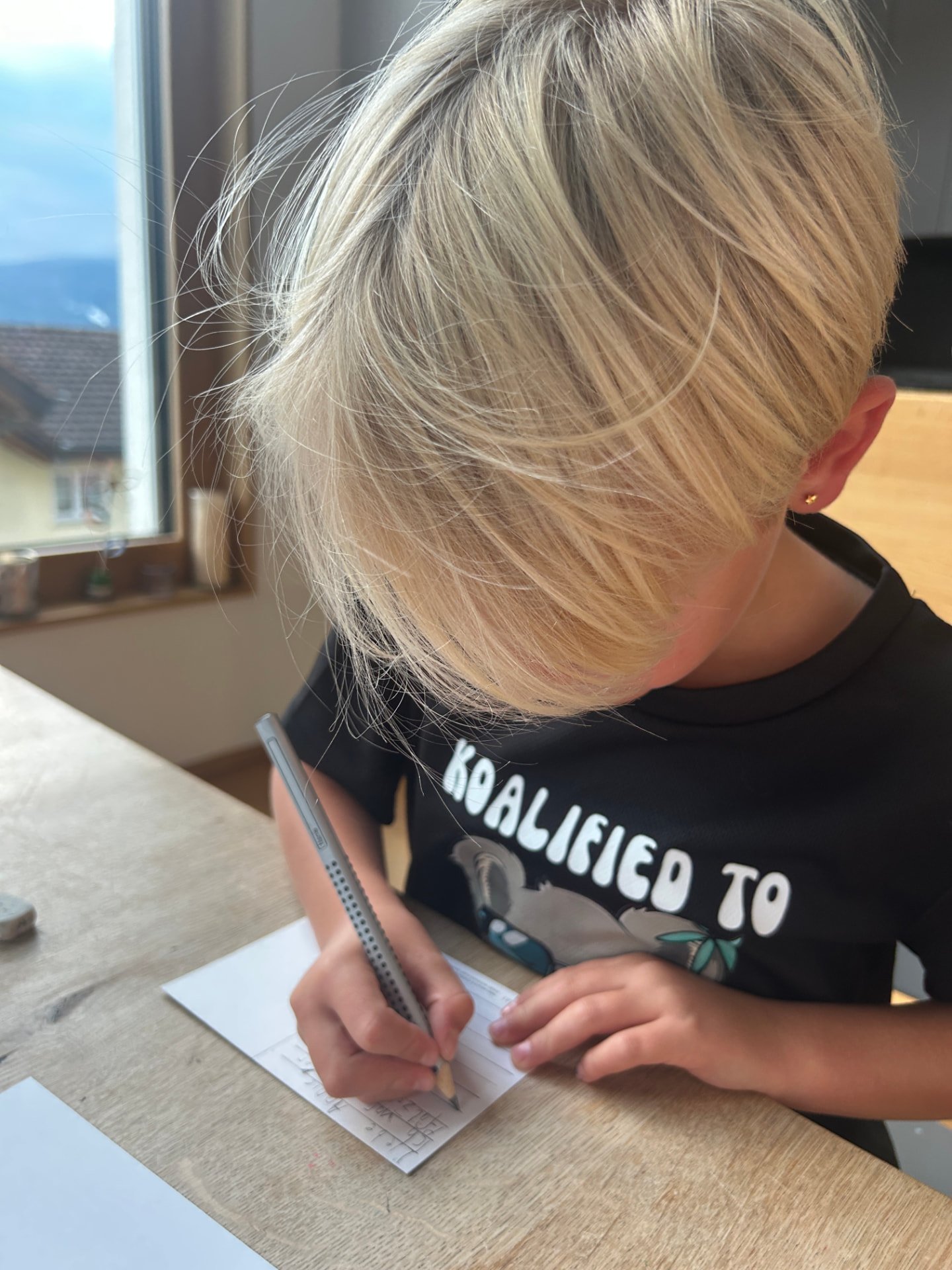 Ein Kind schreibt am Küchentisch einen Brief